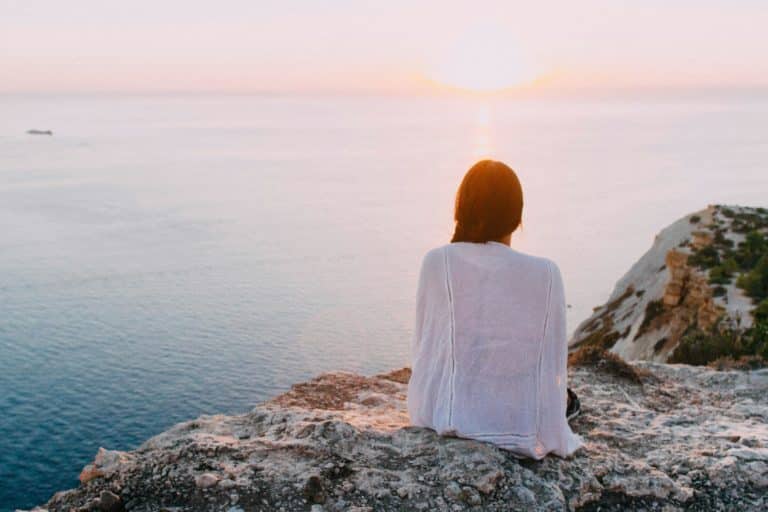 Une femme détendue devant l'immensité de l'océan au coucher du soleil