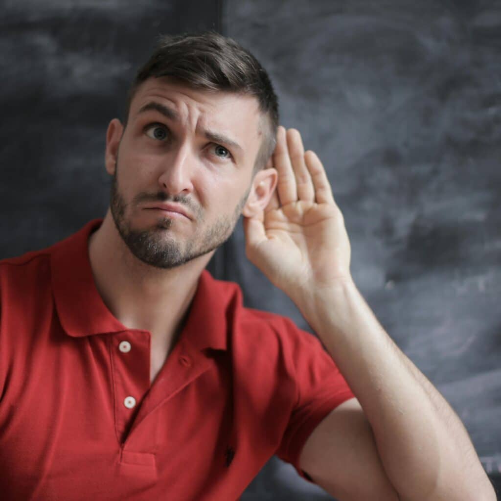 Un homme en polo rouge tend l'oreille